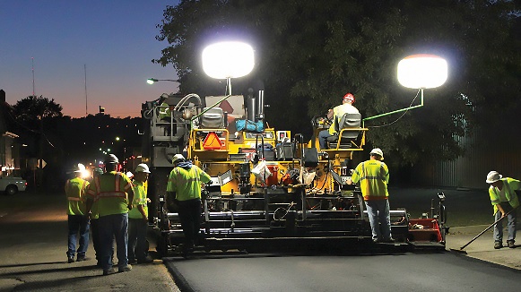 Paving roads at night with balloon safety light on asphalt paving equipment